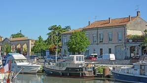 A marina with boats docked, a building with a tiled roof, and a sign for a bakery. - Courry Views: Pool & Nature (Courry)