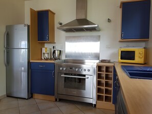 A compact kitchen with a stainless steel refrigerator, a stove, a microwave, and wooden cabinets.