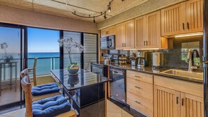 Eine moderne Küche mit Holzausstattung, einer schwarzen Arbeitsplatte und Meerblick.