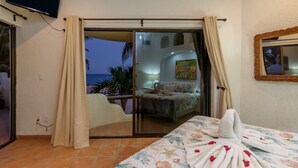 A hotel room with a bed, a TV, and a view of the sea through a sliding door. - Beachfront, Private Pool, close to Downtown San Jose (San Jose del Cabo)