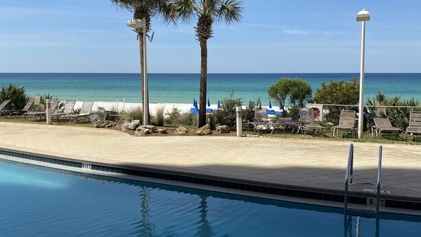 A pool area with a view of the beach and ocean.