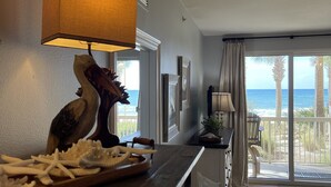 A kitchen with a wooden counter, a decorative bird sculpture, starfish, and a view of the ocean through large sliding doors.