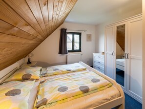 A bedroom with two beds, a window with curtains, a radiator, and a wardrobe.