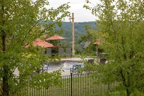 A fenced outdoor area with a small pond, picnic tables, and striped umbrellas. - Big Cedar | Rustic Retreat | Pools, Lake & Adventure (Ridgedale)