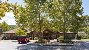 A lodge with a stone facade, a red vehicle parked in front, and a well-maintained lawn. - Big Cedar | Rustic Retreat | Pools, Lake & Adventure (Ridgedale)