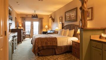 A hotel room with a bed, a desk, a chair, a dresser, and a large wooden tree sculpture.