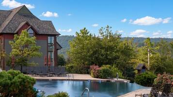 A swimming pool with lounge chairs and a building with a red exterior and a sloped roof.