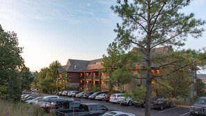 A parking lot with several cars, a building with a sloped roof, and a tree in the foreground. - Big Cedar | Rustic Retreat | Pools, Lake & Adventure (Ridgedale)