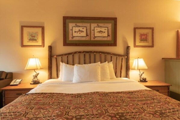 A hotel room with a bed, two bedside lamps, a telephone, and framed pictures on the wall.