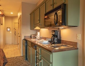 A compact kitchen with a stove, sink, and a microwave.