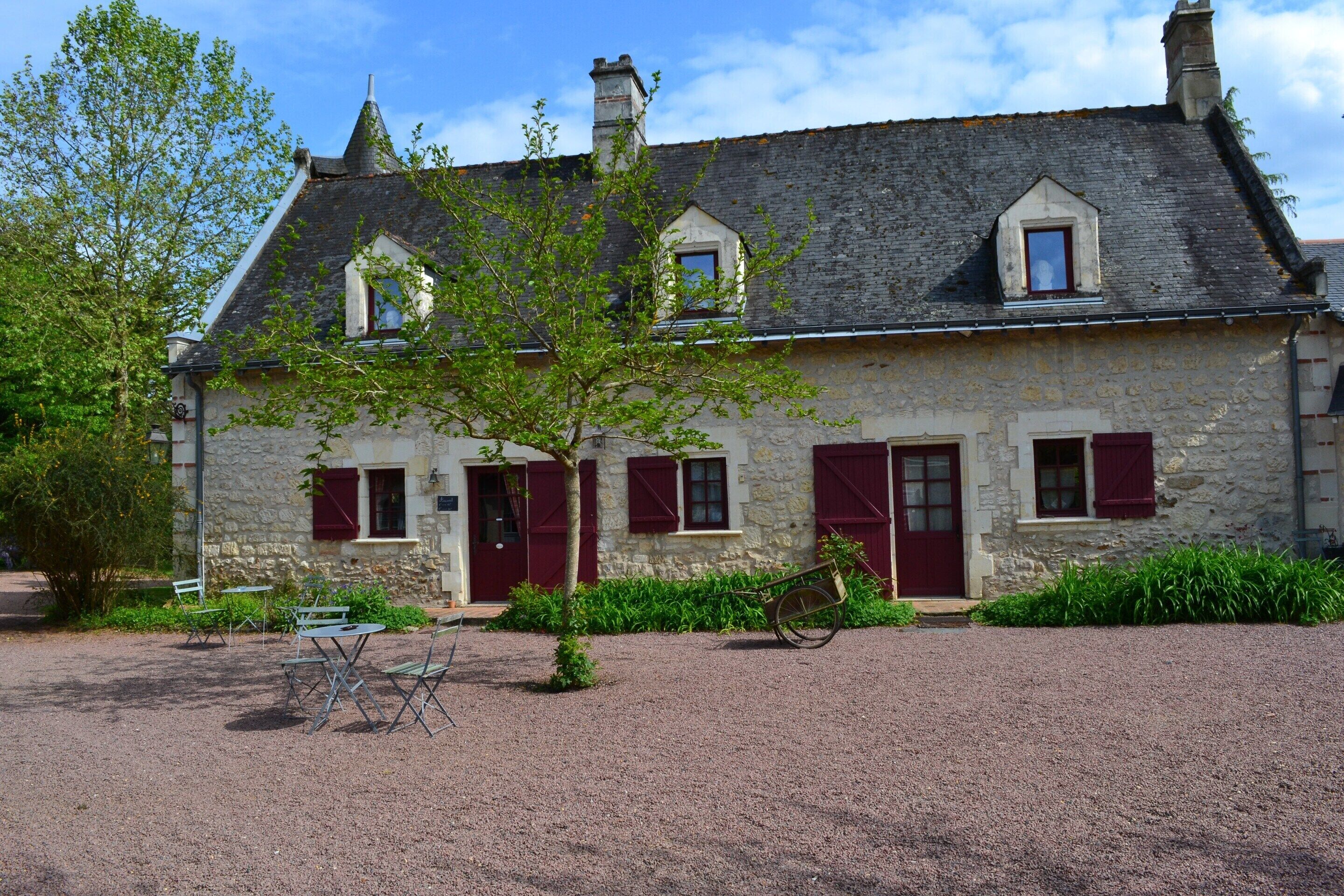 A stone building with a gravel driveway, a bicycle, and outdoor seating.