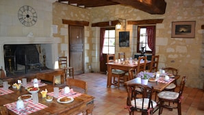 A dining area with wooden tables and chairs, a fireplace, and stone walls. - Romantic Loire Hideaway (Les Bois d'Anjou)