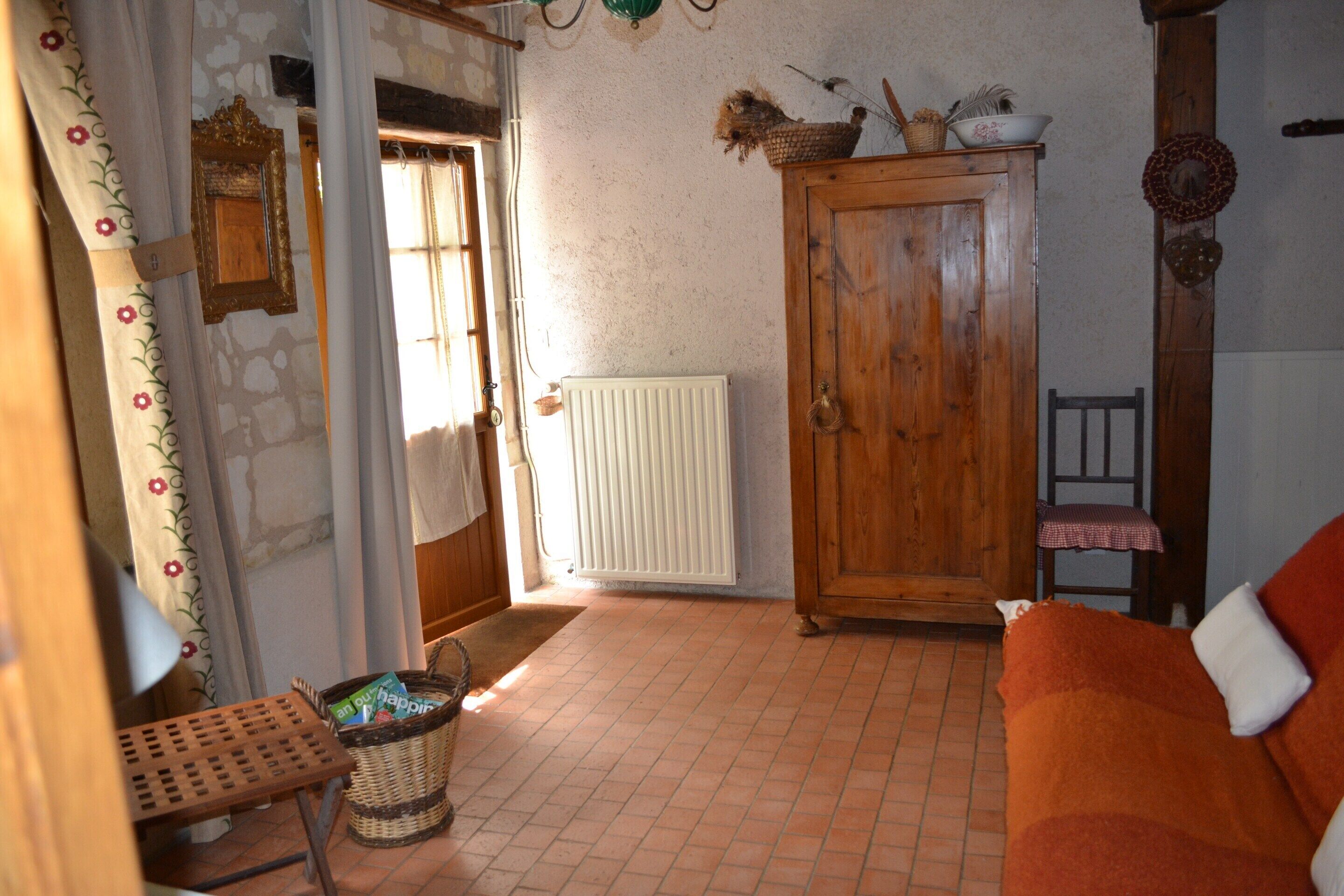 A room with a wooden cabinet, a wicker basket, a radiator, a wooden door, and a red sofa.