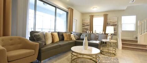 A spacious living room with a large sofa, a coffee table, and a lamp.