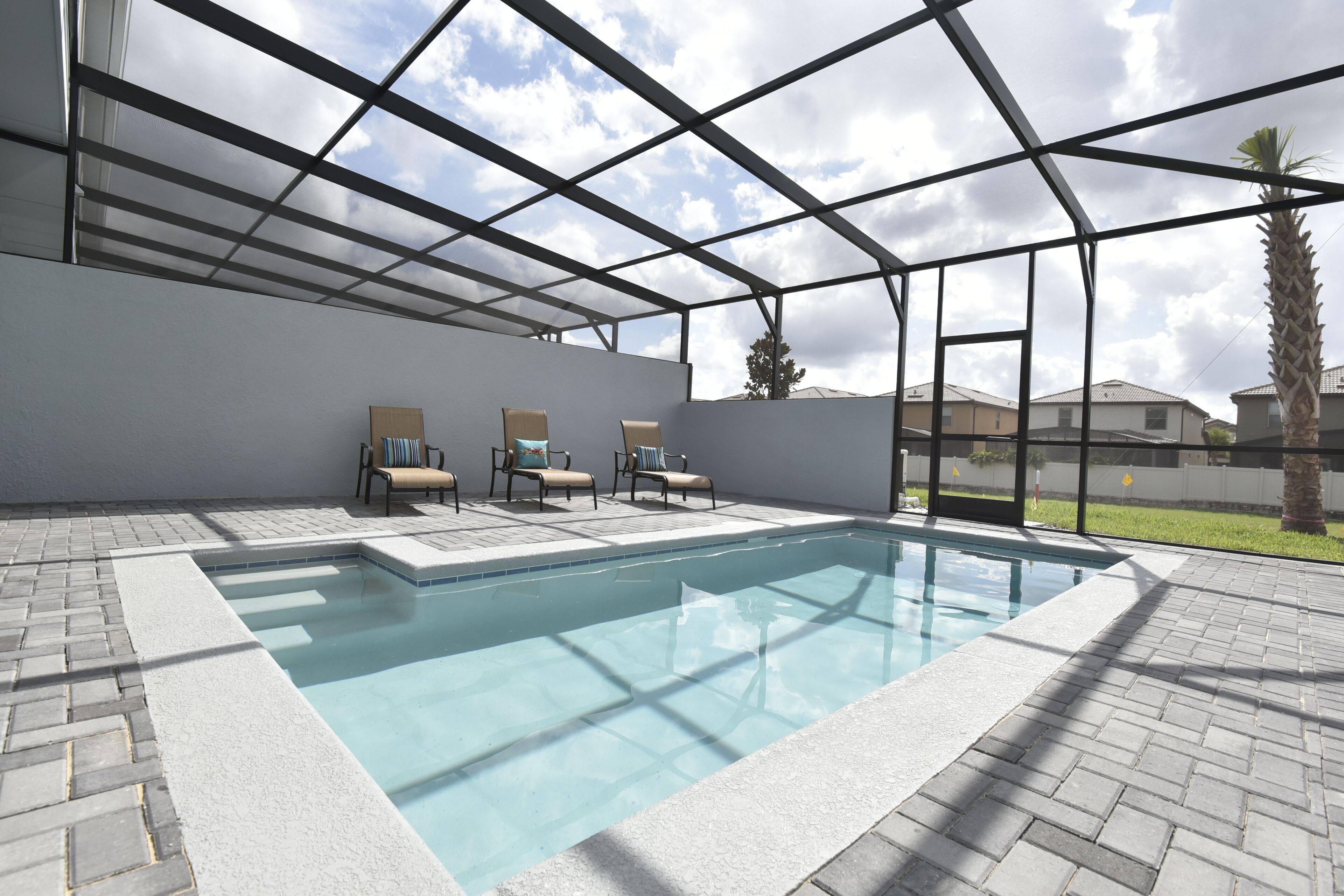 Ein Swimmingpool mit Glasdach, umgeben von Liegestühlen und einer Ziegelterrasse.