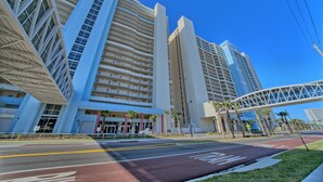 A modern hotel with multiple floors, large windows, and a pedestrian bridge. - Play/Work right at the beach! Fast WiFi, Large balcony, Heated indoor pools (Panama City Beach)