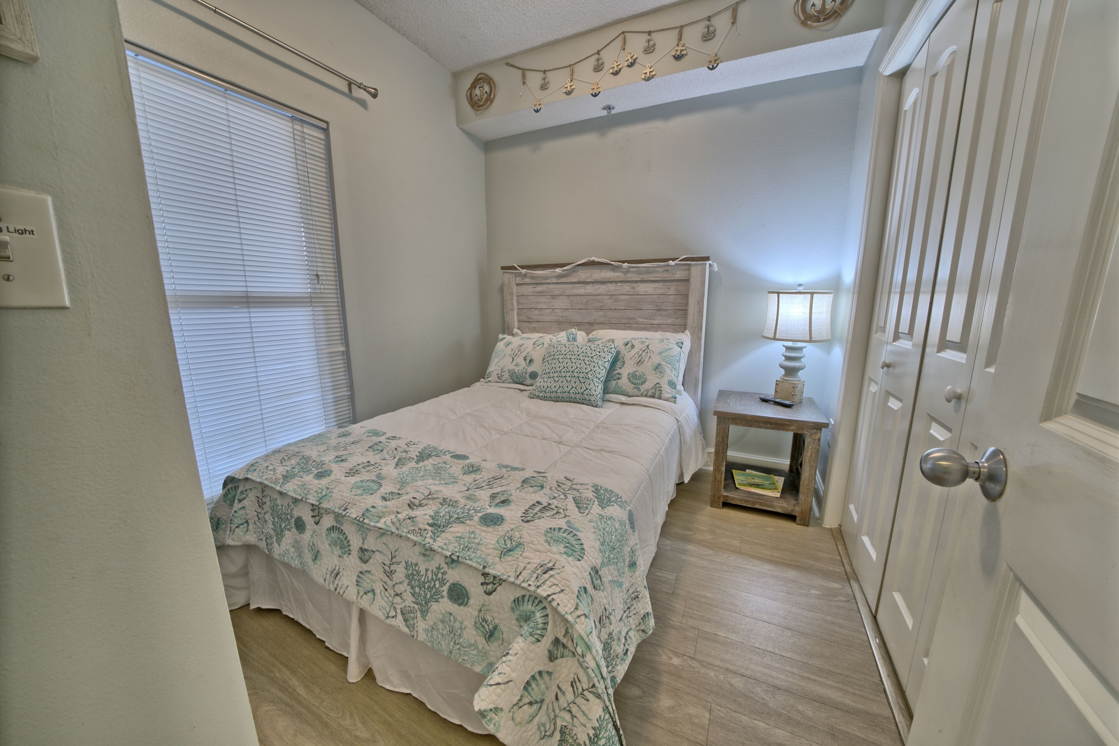 Une chambre à coucher avec un lit, une table de chevet, une lampe et une porte.