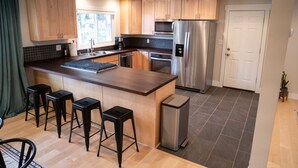 Een moderne keuken met houten kastjes, een roestvrijstalen koelkast, een inbouwoven, een magnetron en een groot kookeiland met barkrukken.