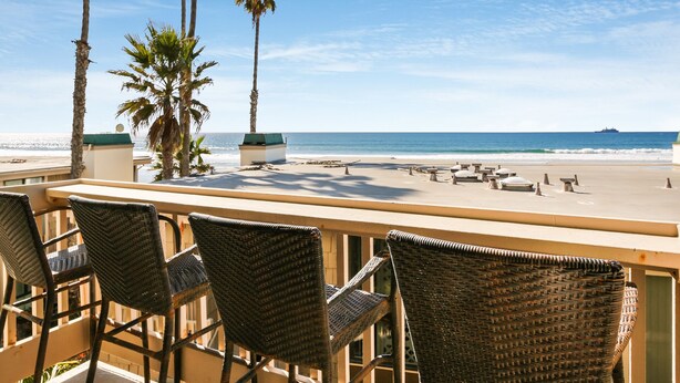 Un bar sulla spiaggia con sedie in vimini e vista sull'oceano.