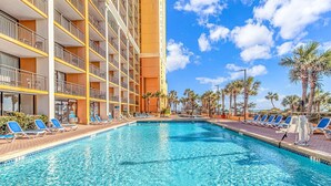 Un hôtel doté d’une piscine, de chaises longues et de palmiers.