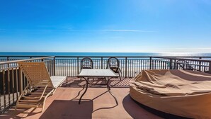 Un balcon avec vue sur l’océan, une table, des chaises et un espace salon abrité.