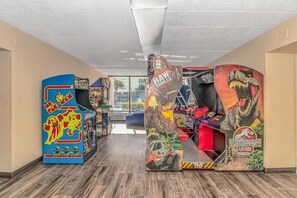 Un pasillo con juegos de arcade, incluyendo Pac-Man y Jurassic Park Arcade, y una vista al exterior.