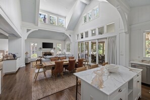A spacious kitchen with a marble island, a dining area with a large table and chairs, and a cozy living room with a fireplace.