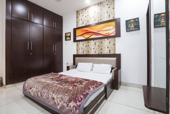Relax in a stylish room with a large bed, floral-patterned bedspread, and geometric-patterned wallpaper.