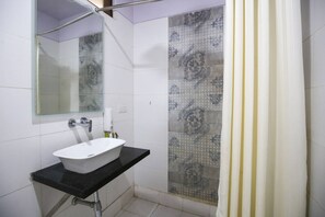 Bathroom features a sink, mirror, and shower area with patterned tiles.