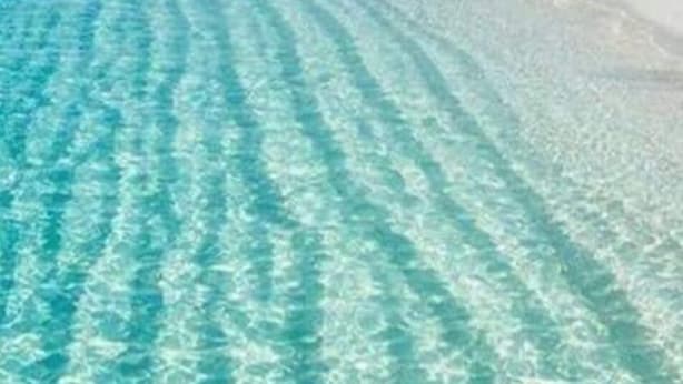 On peut clairement voir une plage avec une eau turquoise et du sable blanc.