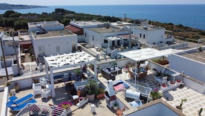 Une terrasse sur le toit avec des espaces de détente en plein air, un coin barbecue et une vue sur la mer.