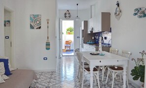 A kitchen with white cabinets, a dining table with chairs, and a view to the outside.