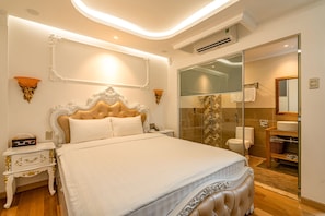 A spacious bedroom with a large bed, a bedside table, a nightstand, and a bathroom with a glass shower enclosure. - S79 Bamboo Hotel 581 Su Van Hanh Street (Ho Chi Minh City)