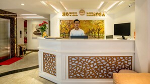 Ein Hotelrezeptionstresen mit einer Uhr und einem Fernseher.