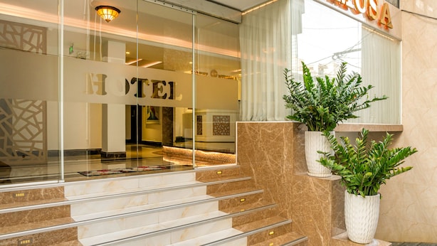 Ein Hotel mit Eingangsbereich, einer Marmortreppe, einer Glastür und Pflanzen in Töpfen.