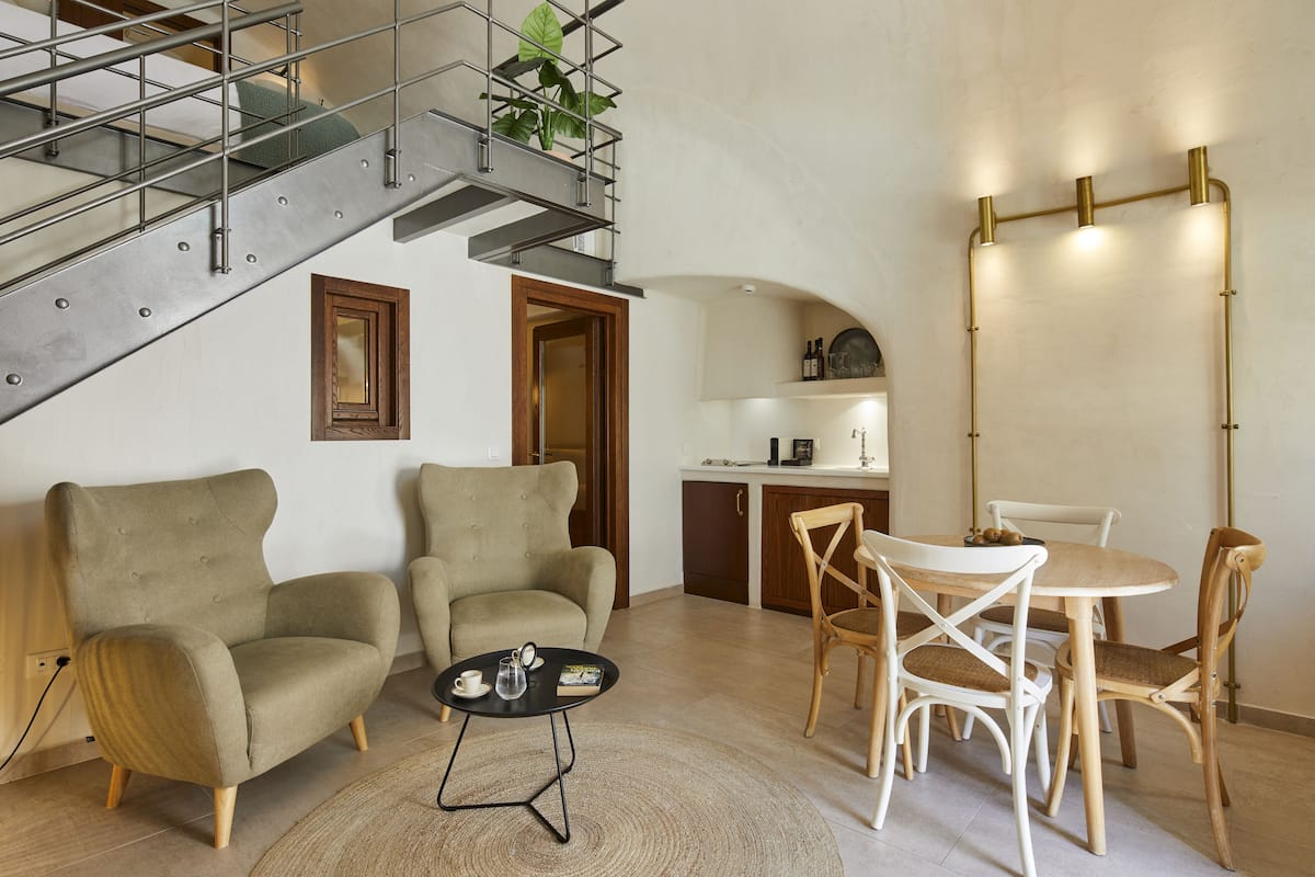 Een moderne woonkamer met een trap, een eethoek met tafel en stoelen, en een keuken met aanrecht en kasten.