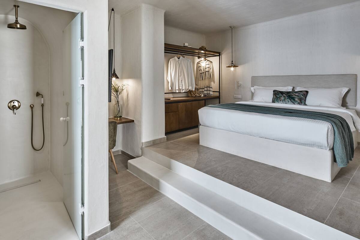 Een moderne slaapkamer met een groot bed, een inloopkast en een douchegedeelte.