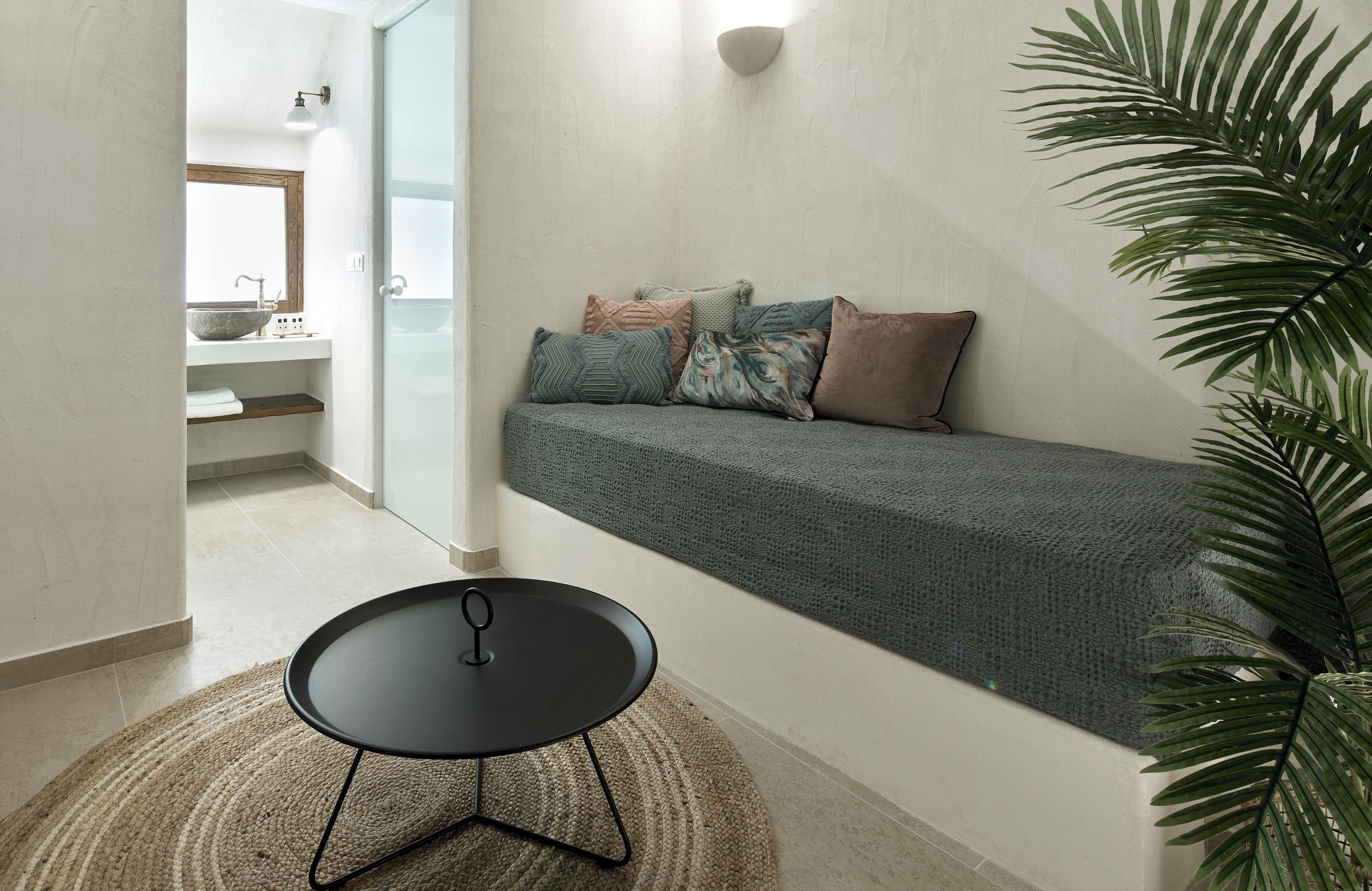 A modern bathroom with a built-in sink and a cozy seating area with a green blanket and pillows.