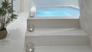 Un área de spa moderna con un jacuzzi, escalones que lo conducen y una planta en maceta.