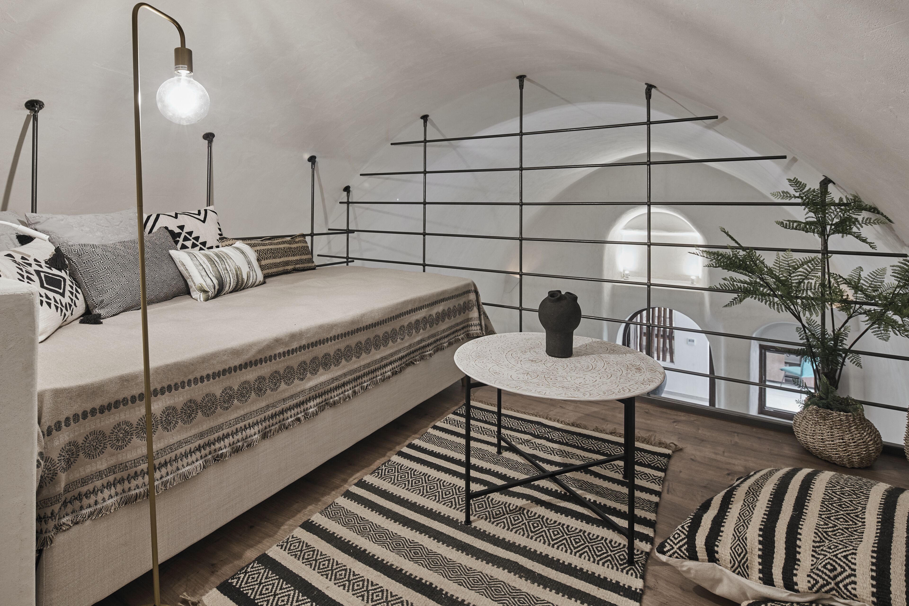 Un dormitorio tipo loft acogedor, con una cama, una mesita redonda pequeña y una planta en maceta.