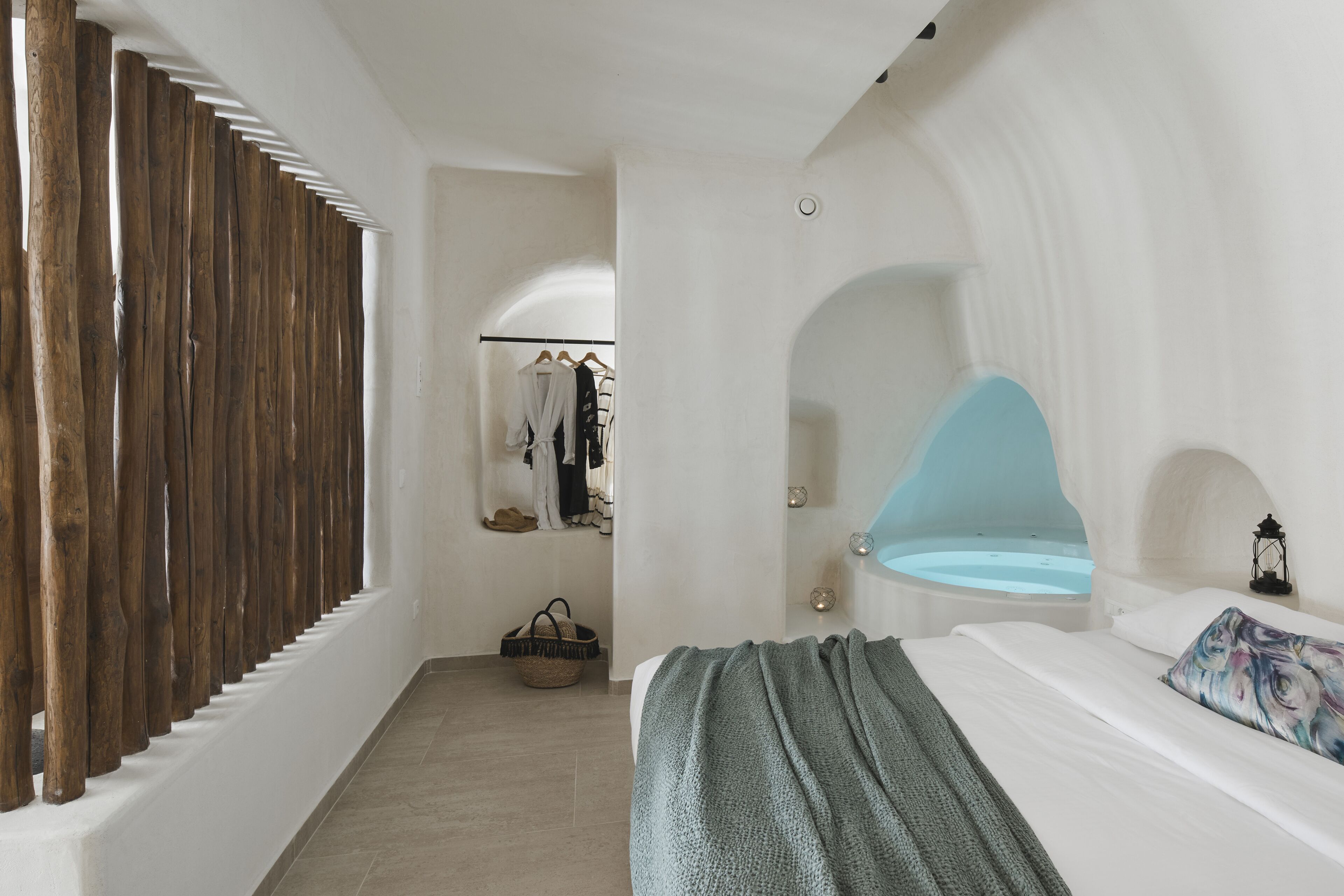 A bedroom with a large bed, a blue bathtub, and a wooden wall.