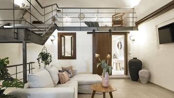Una sala de estar moderna con una escalera, un sofá, una mesa de centro y un jarrón grande.