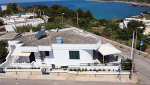 Un bâtiment moderne de couleur blanche, doté d’un toit plat, de panneaux solaires et d’un espace extérieur aménagé avec des sièges.