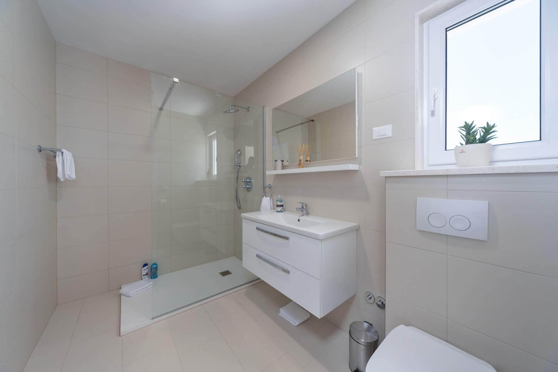 Un bagno moderno con doccia vetro, lavabo bianco e WC.