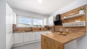 Een moderne keuken met witte kasten, een houten kookeiland en een inbouwoven.