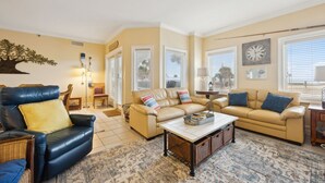 A living room with a blue leather armchair, beige sofas, and a patterned rug.