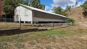 A single-story building with a green roof and a fenced yard. - Meyenburg Unit 4, 1 Double Beds, 1 Single 3 pax (Mount Morgan)