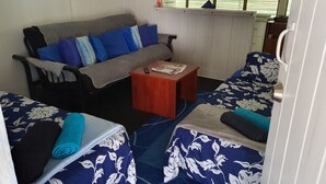 A compact room with a sofa, two single beds, a small table, and a window with blinds. - Meyenburg Unit 4, 1 Double Beds, 1 Single 3 pax (Mount Morgan)