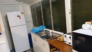 A compact kitchen with a refrigerator, sink, and a microwave. - Meyenburg Unit 4, 1 Double Beds, 1 Single 3 pax (Mount Morgan)