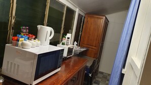 A kitchen with a microwave, kettle, and various food items on the counter. - Meyenburg Unit 4, 1 Double Beds, 1 Single 3 pax (Mount Morgan)